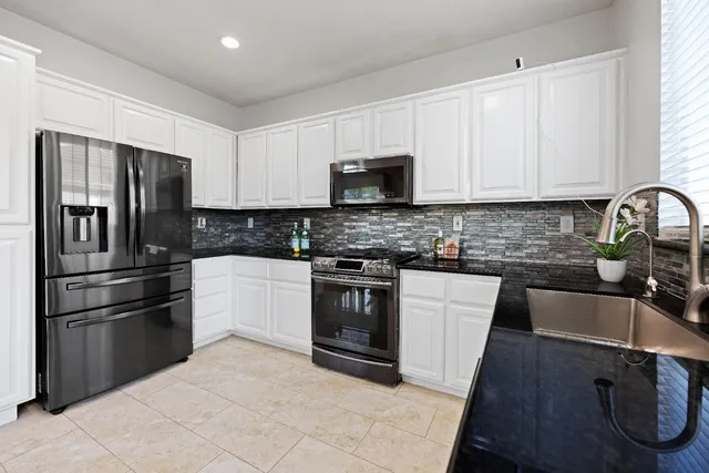 a kitchen with granite countertop a refrigerator stove and sink