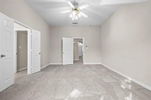 a view of an empty room and chandelier fan