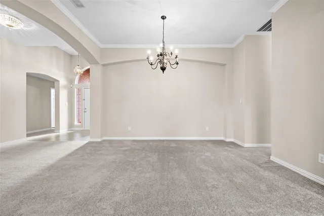 a view of an empty room with a chandelier fan
