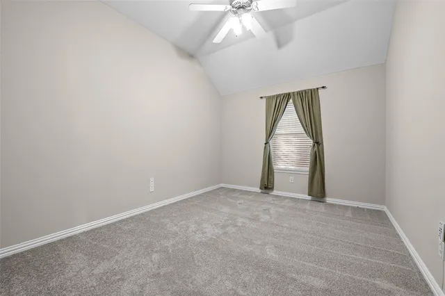 an empty room with a chandelier fan and windows
