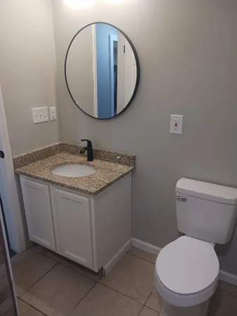 a bathroom with a granite countertop toilet a sink and mirror
