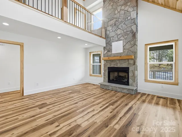 a view of an empty room with wooden floor fireplace and a window