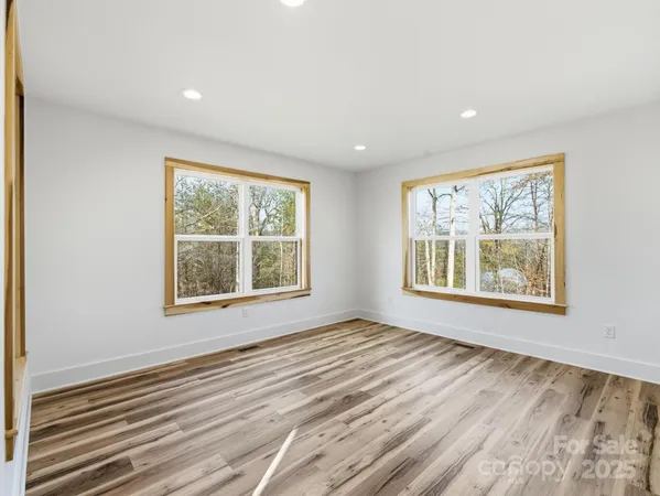 a view of an empty room with a window and a dresser