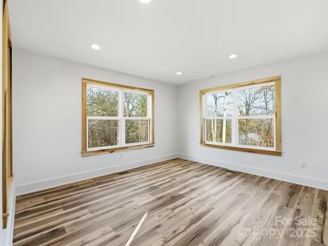 a view of an empty room with a window and a dresser