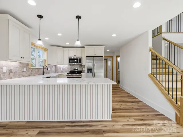 a kitchen with stainless steel appliances granite countertop a sink window and a chandelier