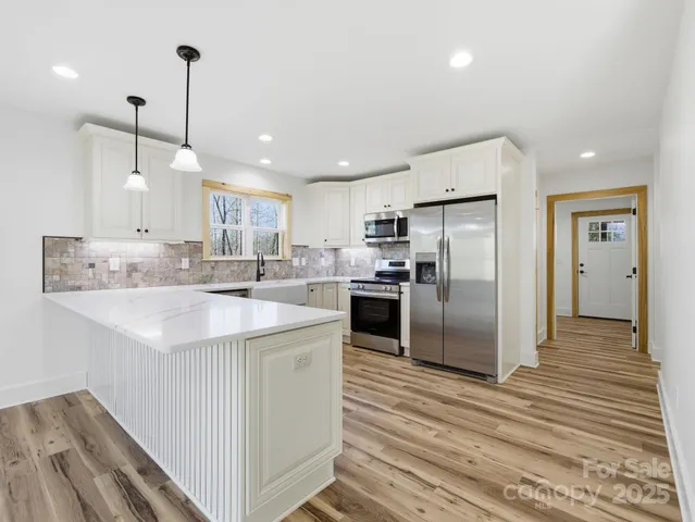 a kitchen with kitchen island a refrigerator a sink and wooden floor