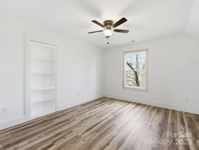wooden floor in an empty room with a chandelier fan
