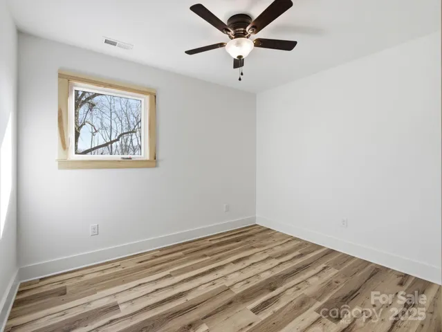 a view of a room with wooden floor and ceiling fan
