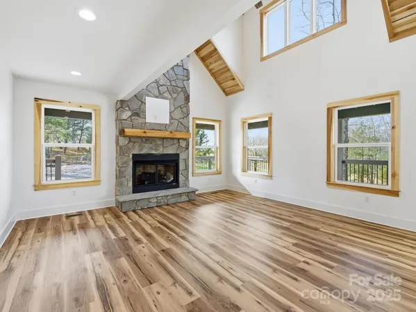a view of an empty room with wooden floor fireplace and a window