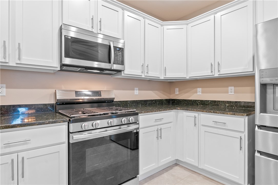 6045 Red Maple Manor Vero Beach, FL 32966 - Photo 8 of 36 a kitchen with granite countertop white cabinets and stainless steel appliances