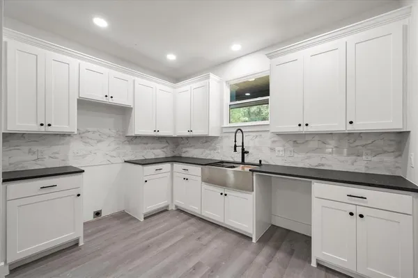 a kitchen with stainless steel appliances granite countertop a sink and cabinets with wooden floor