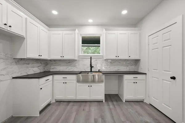 a kitchen with granite countertop white cabinets white appliances a sink and a window