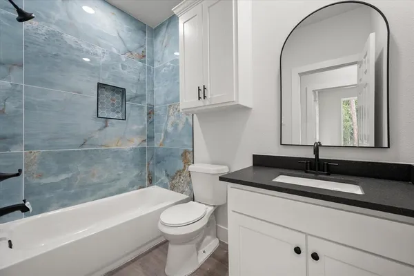 a bathroom with a granite countertop sink a toilet and bathtub