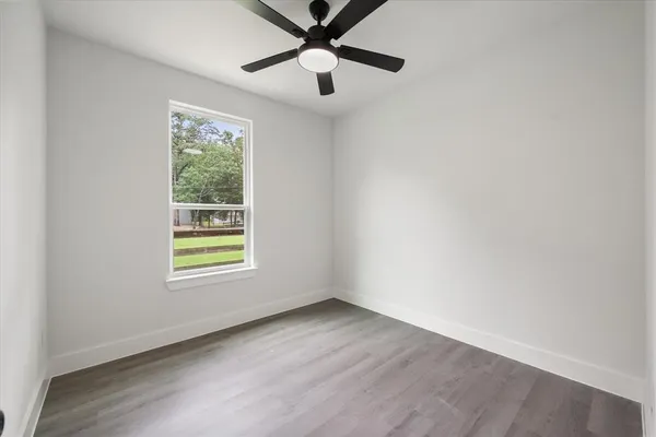 an empty room with a window and a ceiling fan