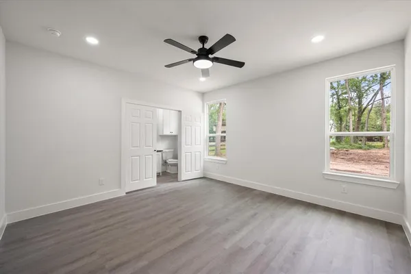 a view of an empty room with a window and wooden floor