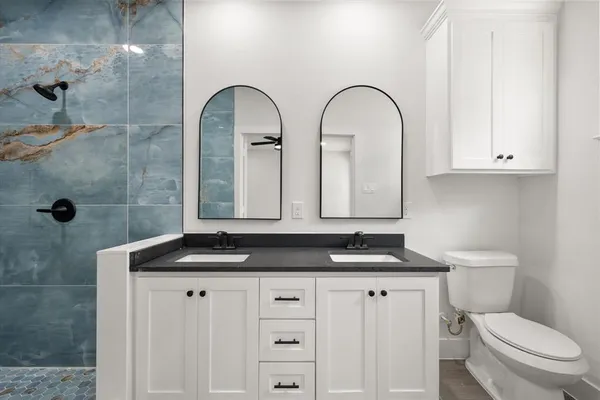 a bathroom with a granite countertop sink a toilet and a shower