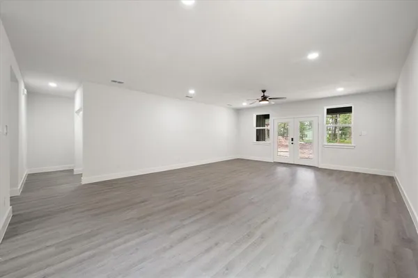 an empty room with wooden floor and windows