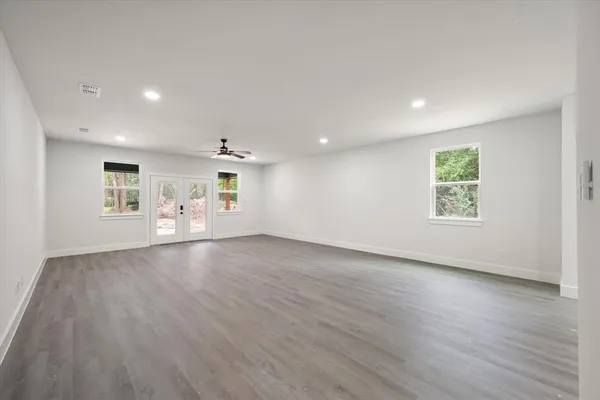an empty room with wooden floor ceiling fan and windows