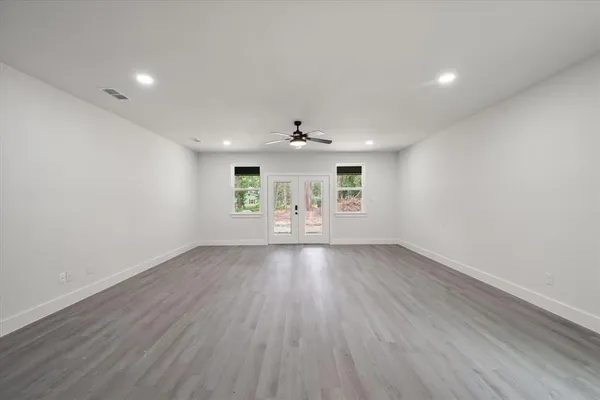an empty room with wooden floor and windows