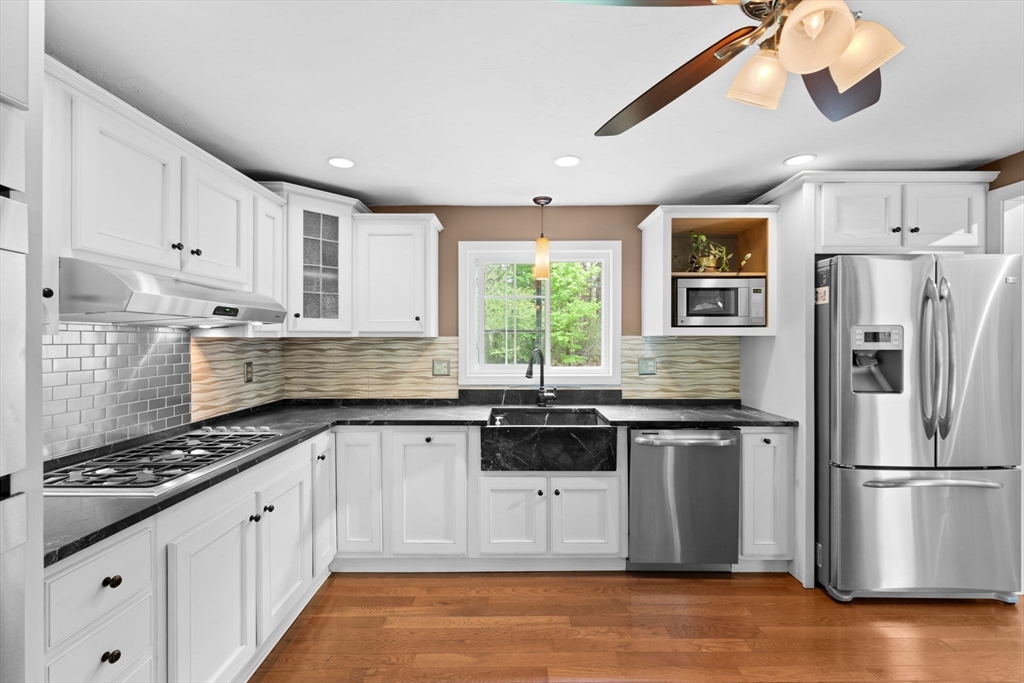 103 Maple Street Plympton, MA 02367 - Photo 5 of 41 a kitchen with stainless steel appliances granite countertop a stove a sink dishwasher a refrigerator and white cabinets with wooden floor