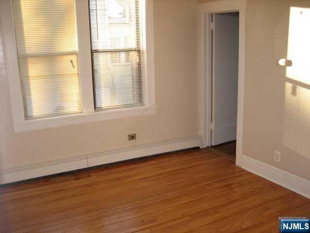 75 Barkley Avenue, Unit 4 Clifton, NJ 07011 - Photo 5 of 10 an empty room with wooden floor and windows