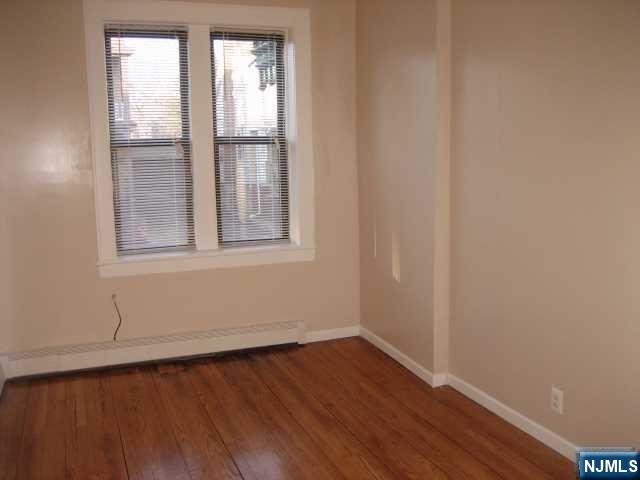 75 Barkley Avenue, Unit 4 Clifton, NJ 07011 - Photo 6 of 10 an empty room with wooden floor and windows