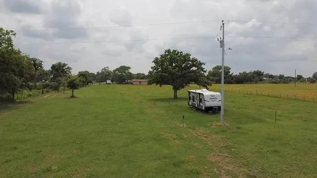 a view of a green field with trees in the background