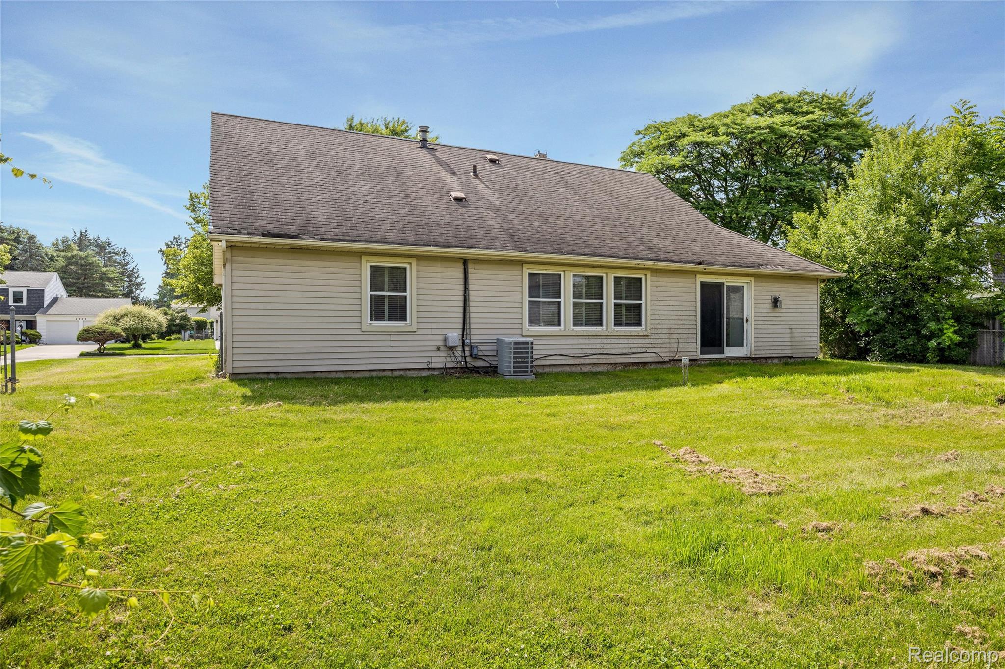 4942 Butler Drive Troy, MI 48085 - Photo 32 of 33 Rear exterior with beige siding, a dark shingle roof, and multiple windows