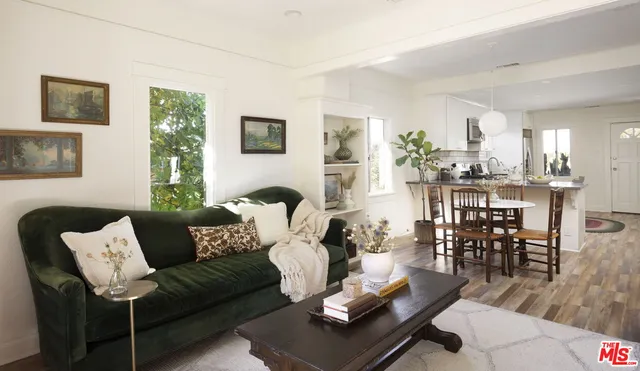 a living room with furniture wooden floor and kitchen view