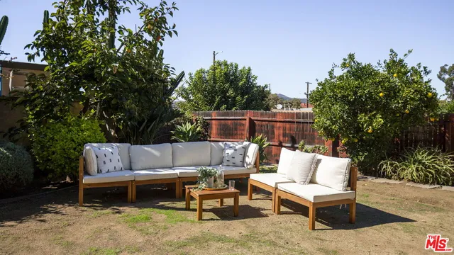 a view of a patio with couches and a table and chairs with wooden fence