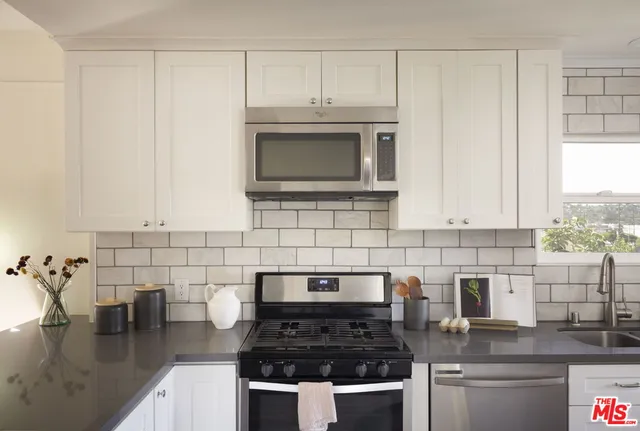 a kitchen with granite countertop a stove a sink and a microwave