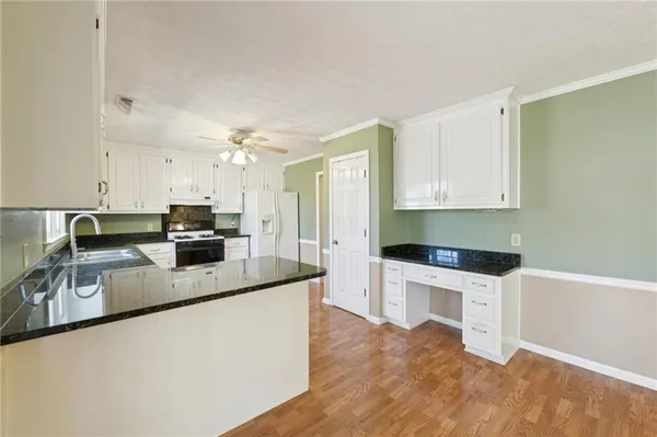 a kitchen with granite countertop a sink a stove top oven and cabinetry