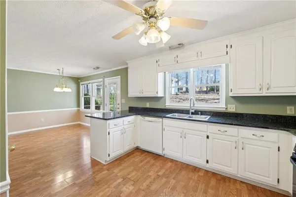 a kitchen with granite countertop white cabinets white appliances a sink and a window