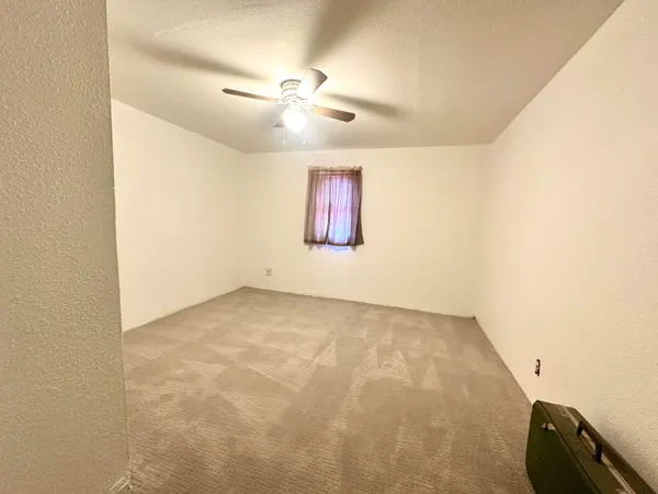 an empty room with windows and fan