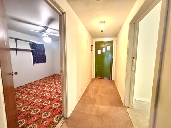 a view of hallway with wooden floor and bathroom