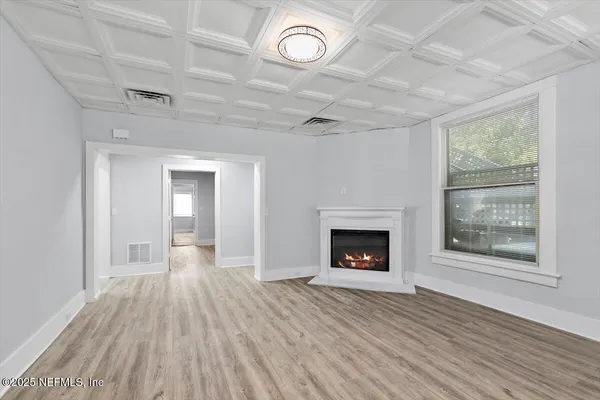 an empty room with wooden floor fireplace and windows