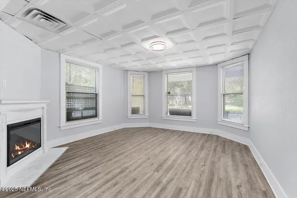 a view of an empty room with wooden floor fireplace and a window