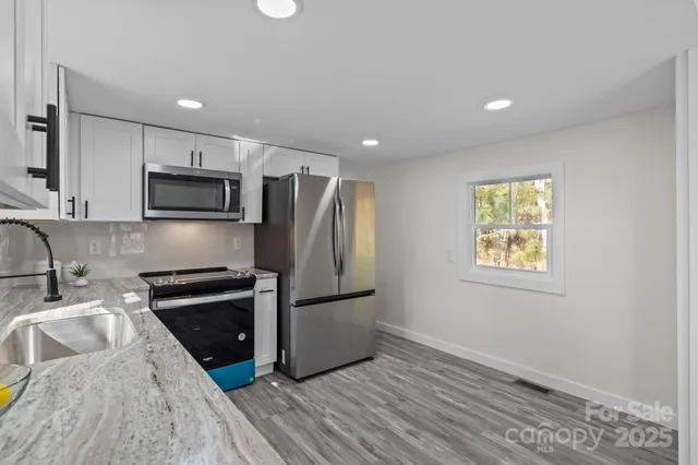 a kitchen with granite countertop a refrigerator stove and sink