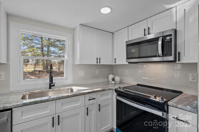 a kitchen with stainless steel appliances granite countertop a sink stove and microwave