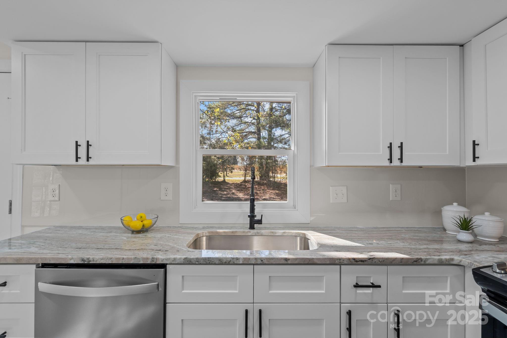 2627 McCallum Road Candor, NC 27229 - Photo 18 of 41 a kitchen with granite countertop a sink white cabinets and a window
