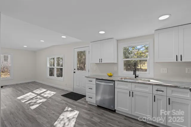 a open kitchen with granite countertop a sink window and cabinets