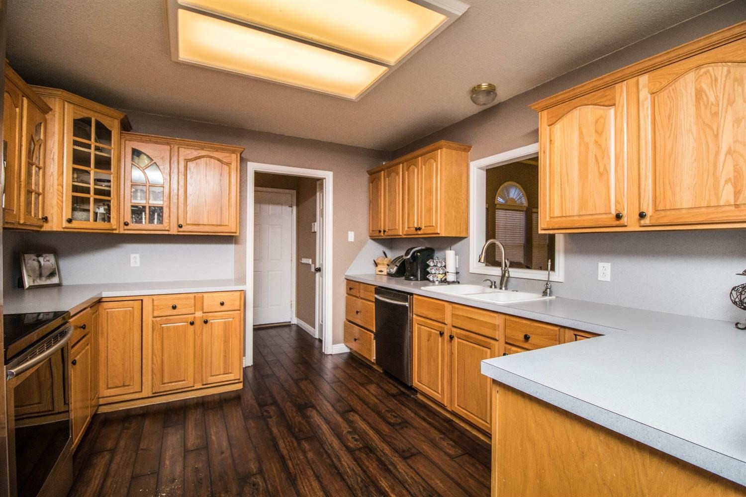 5821 89th Street Lubbock, TX 79424 - Photo 7 of 19 a kitchen with stainless steel appliances granite countertop wooden cabinets a sink and dishwasher a stove with wooden floor