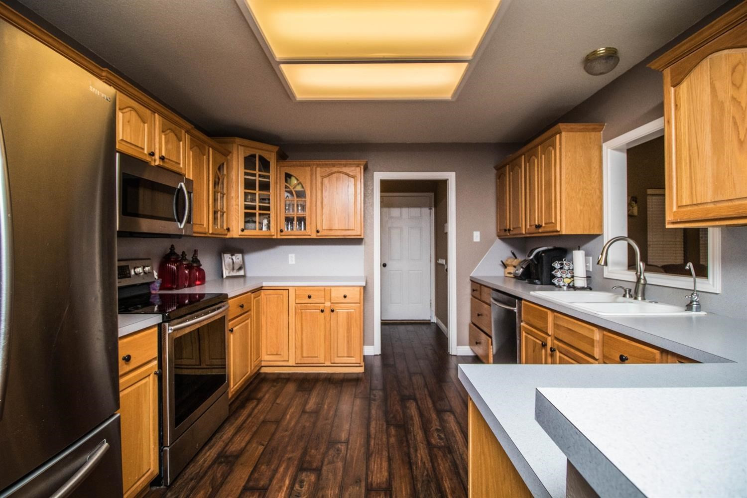 5821 89th Street Lubbock, TX 79424 - Photo 8 of 19 a kitchen with stainless steel appliances granite countertop wooden cabinets a stove top oven a sink and dishwasher with wooden floor