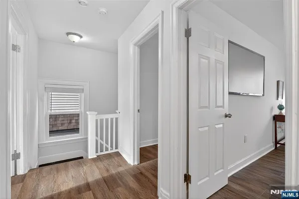 a view of a hallway with entryway and wooden floor