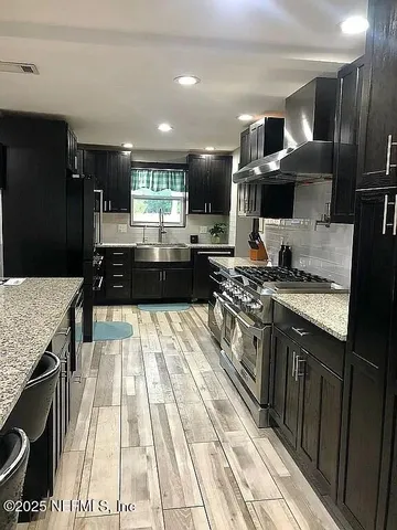 a kitchen with stainless steel appliances kitchen island granite countertop a table chairs sink and cabinets