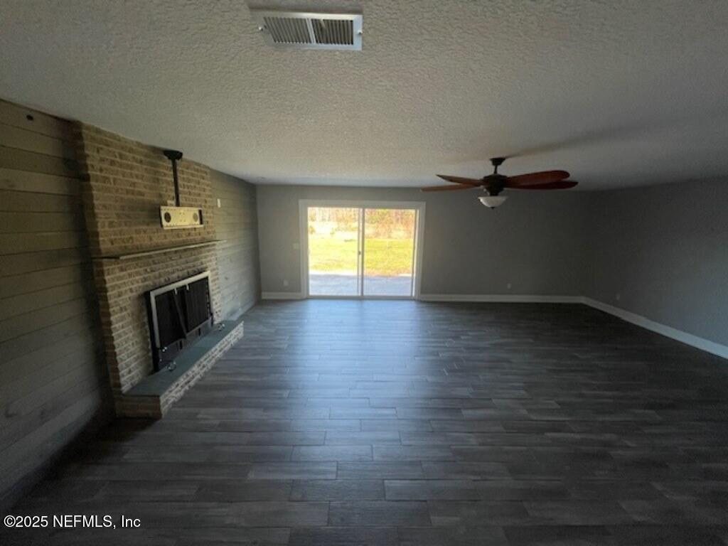 14014 Lem Turner Road Jacksonville, FL 32218 - Photo 15 of 25 an empty room with wooden floor fireplace and windows