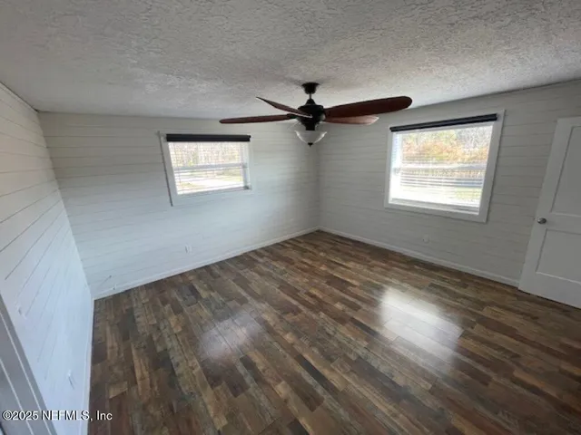 an empty room with wooden floor cabinet and windows