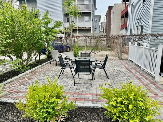 a view of a patio with table and chairs potted plants and large tree