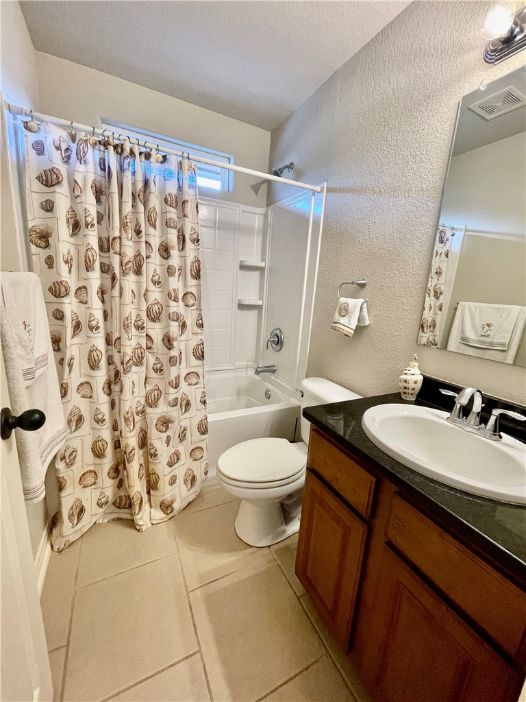 103 Sandollar Circle Fulton, TX 78382 - Photo 18 of 25 a bathroom with a granite countertop sink a toilet and shower curtain