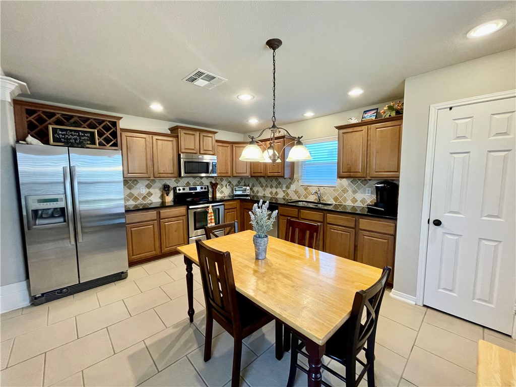 103 Sandollar Circle Fulton, TX 78382 - Photo 9 of 25 a kitchen with stainless steel appliances granite countertop a refrigerator a stove a sink a dining table and chairs